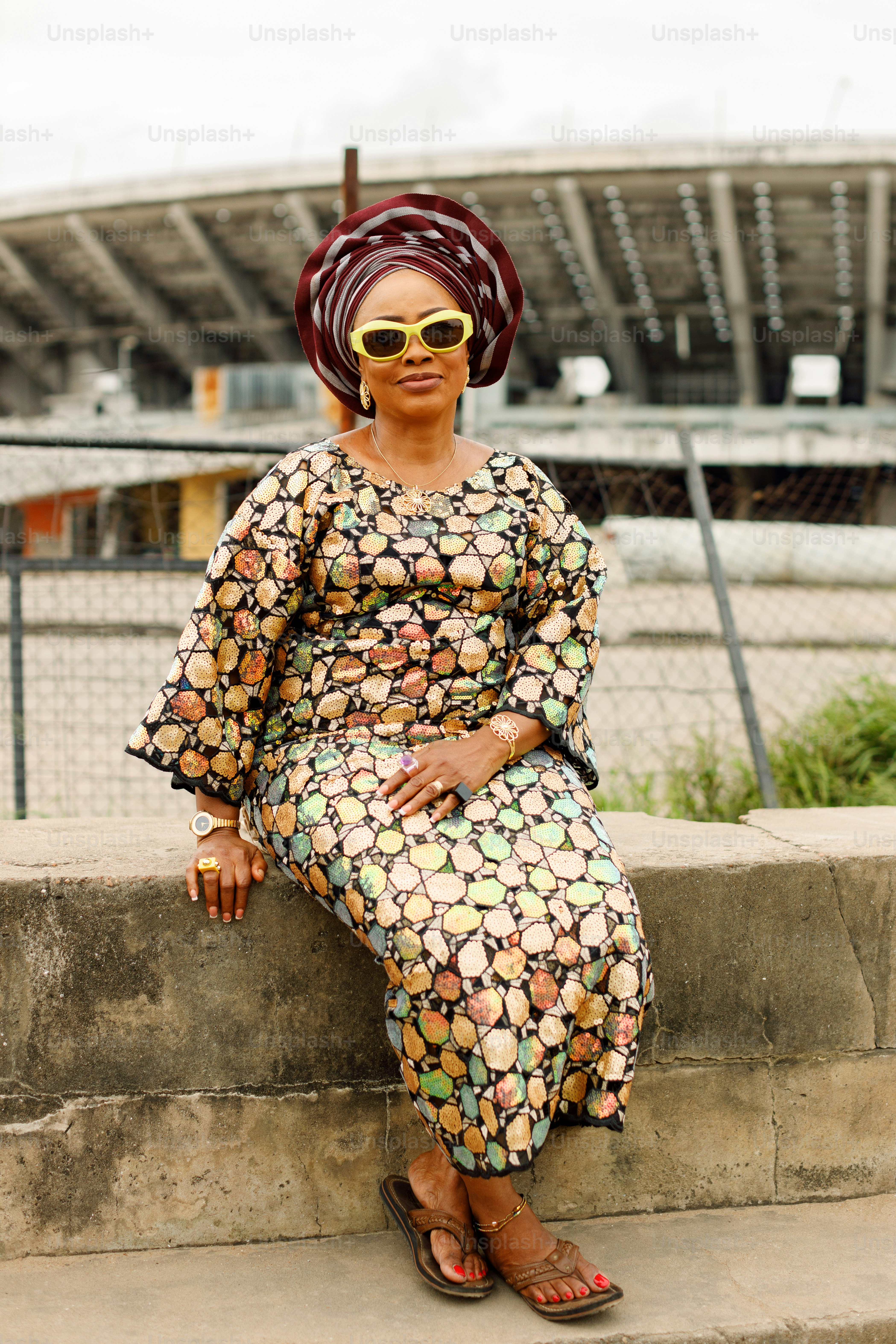 a woman sitting on a ledge wearing sunglasses