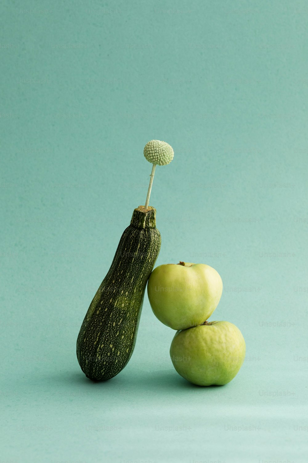 um pepino e duas maçãs verdes em um fundo azul