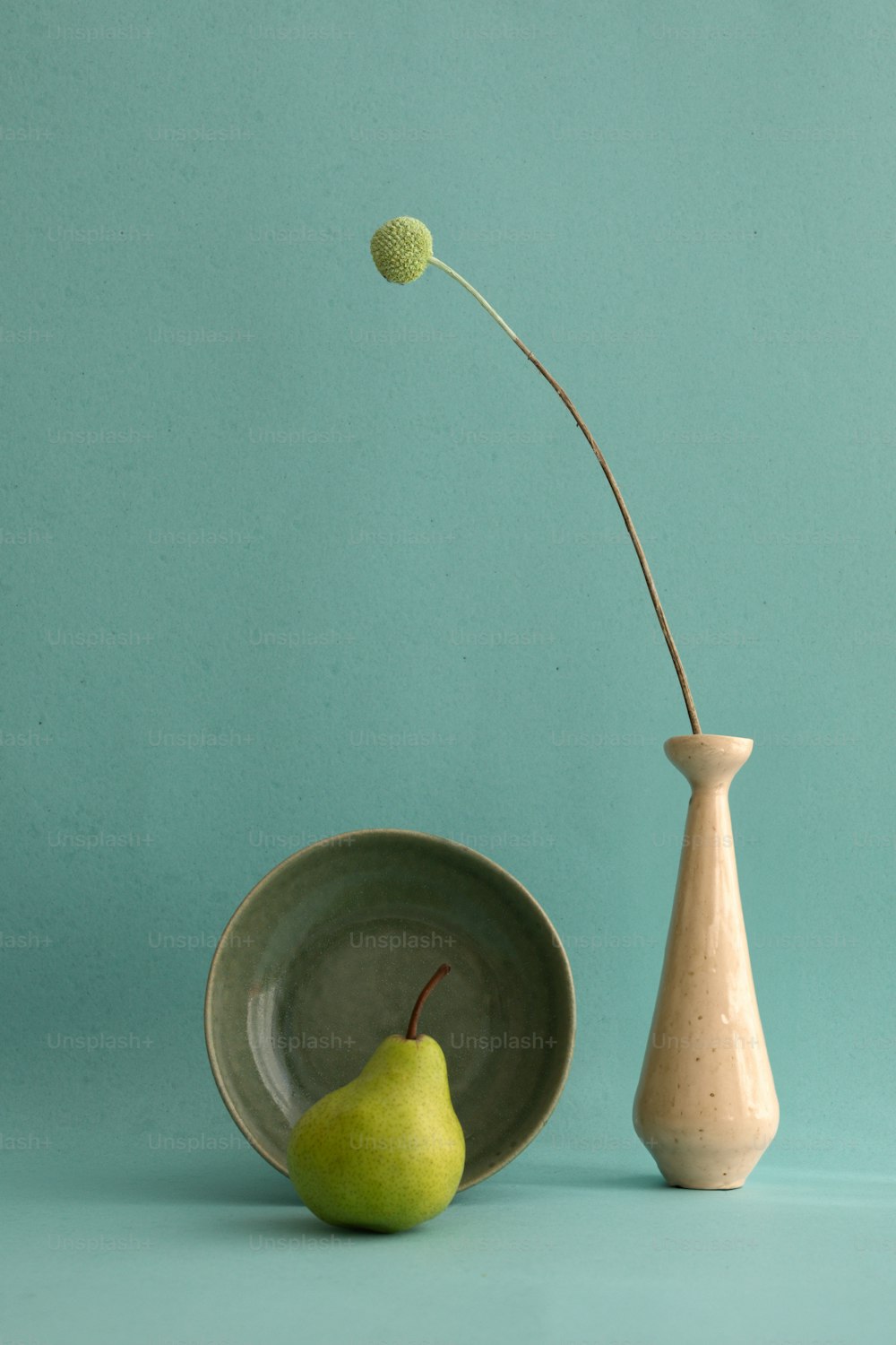 a pear sitting next to a vase with a flower in it