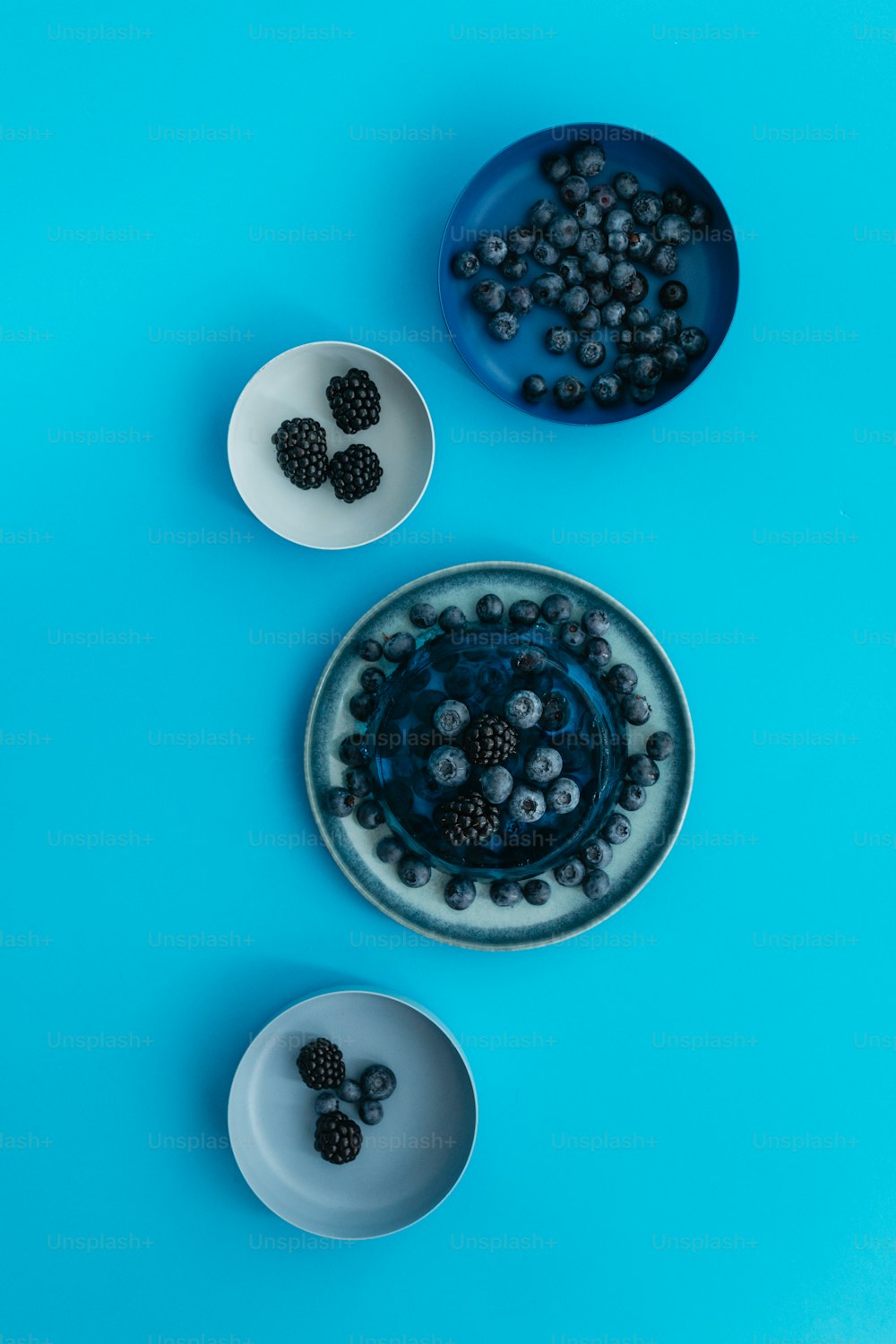 파란색 배경에 딸�기 한 그릇과 블랙베리 한 그릇