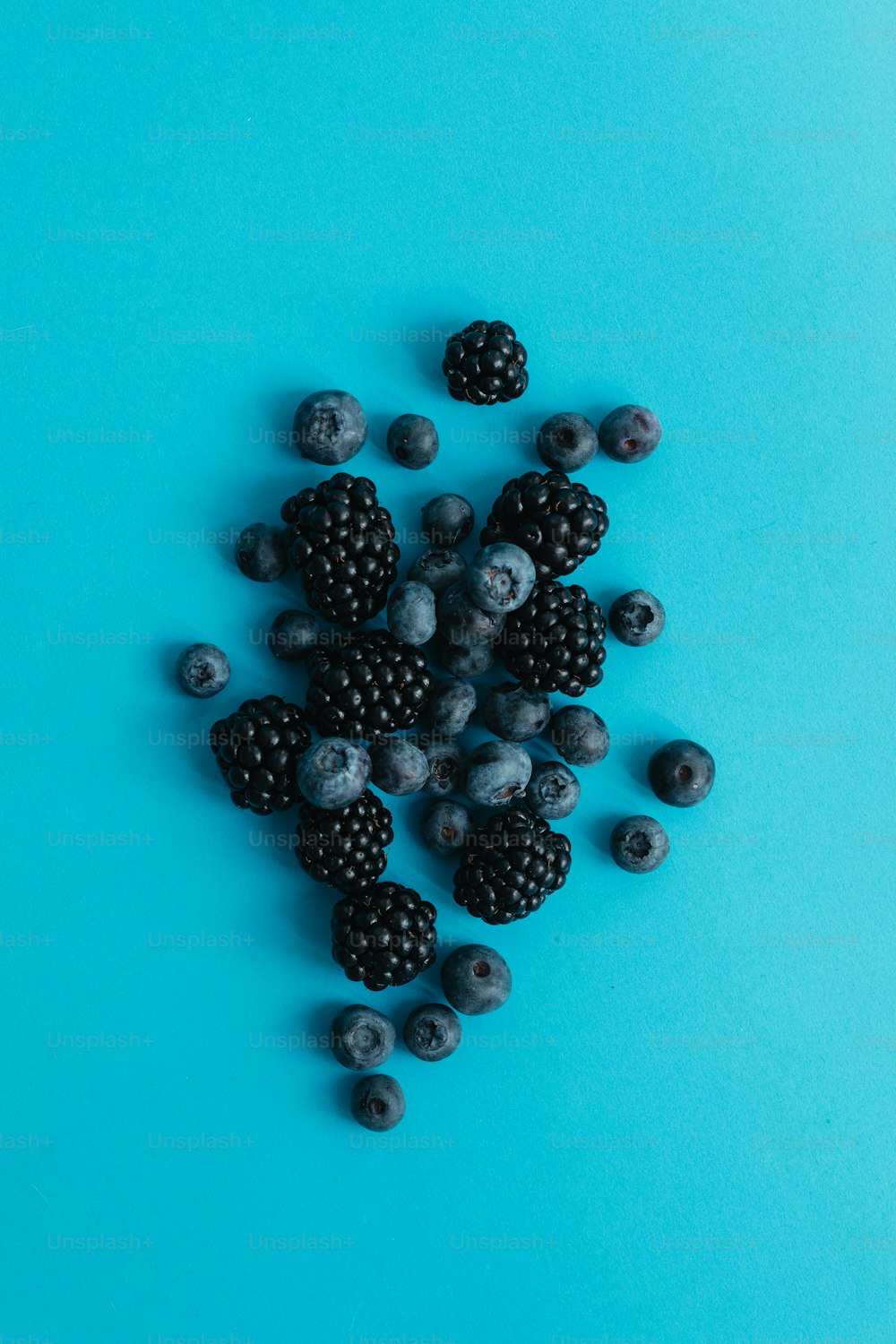 a pile of berries and blueberries on a blue background