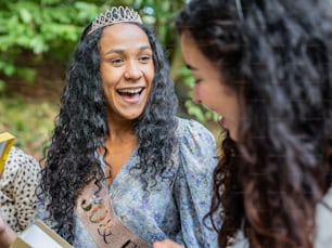 a woman wearing a tiara and smiling at another woman