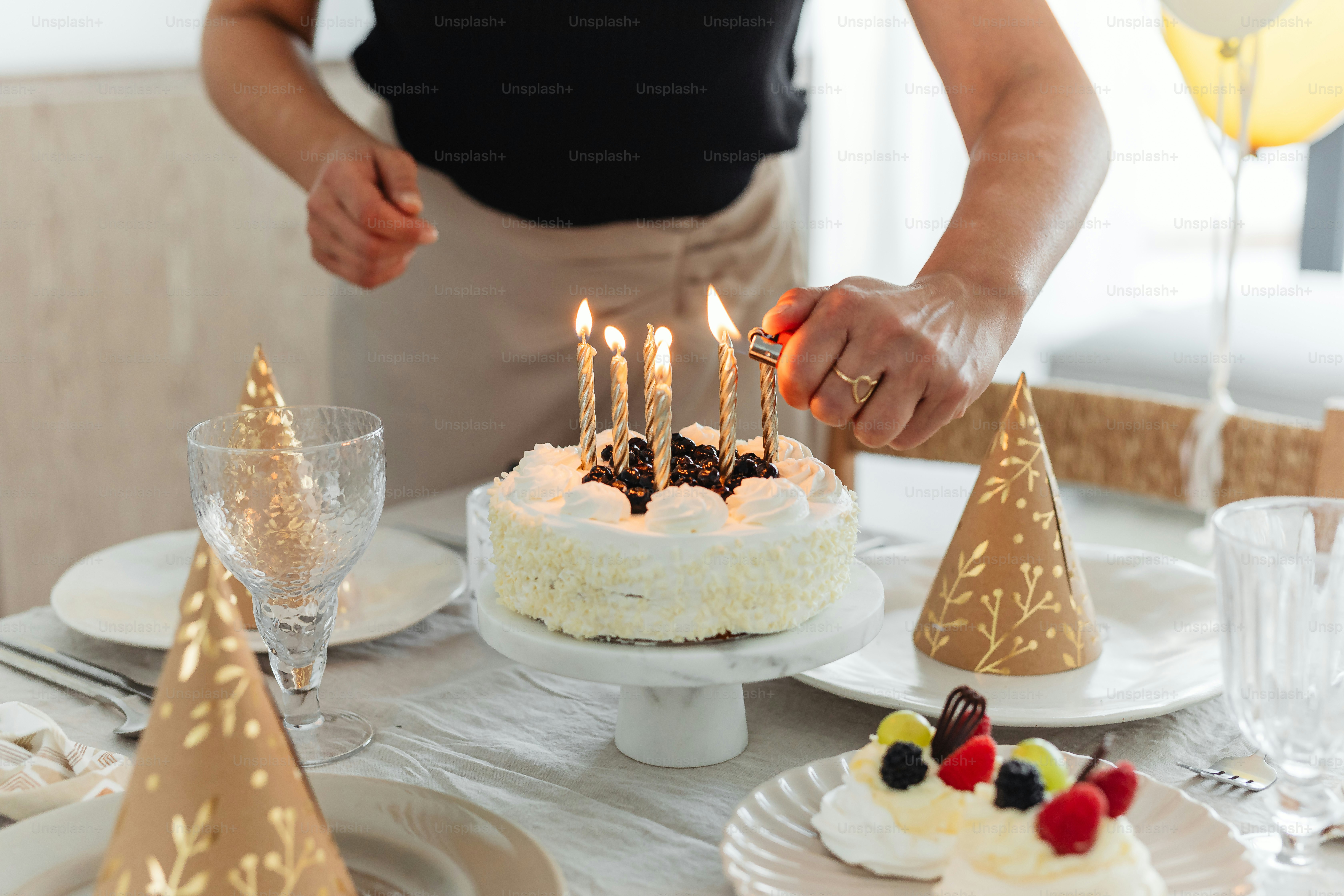 a woman lighting candles on a cake on a table