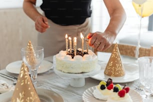 a woman lighting candles on a cake on a table