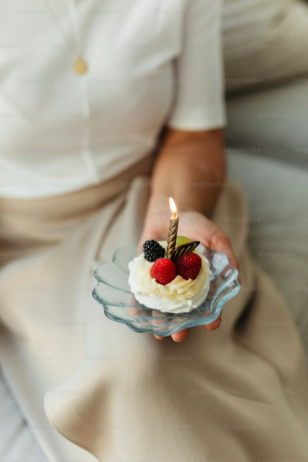 a woman holding a small cake with a candle on top of it