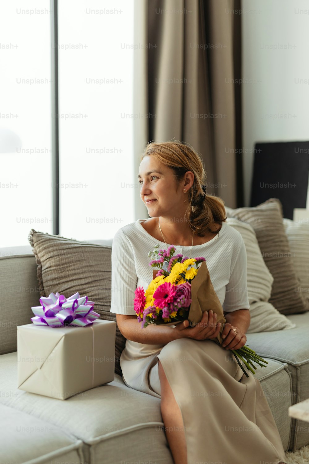a woman sitting on a couch holding a bouquet of flowers