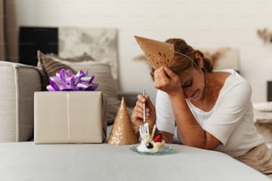 a woman sitting at a table with a birthday hat on her head