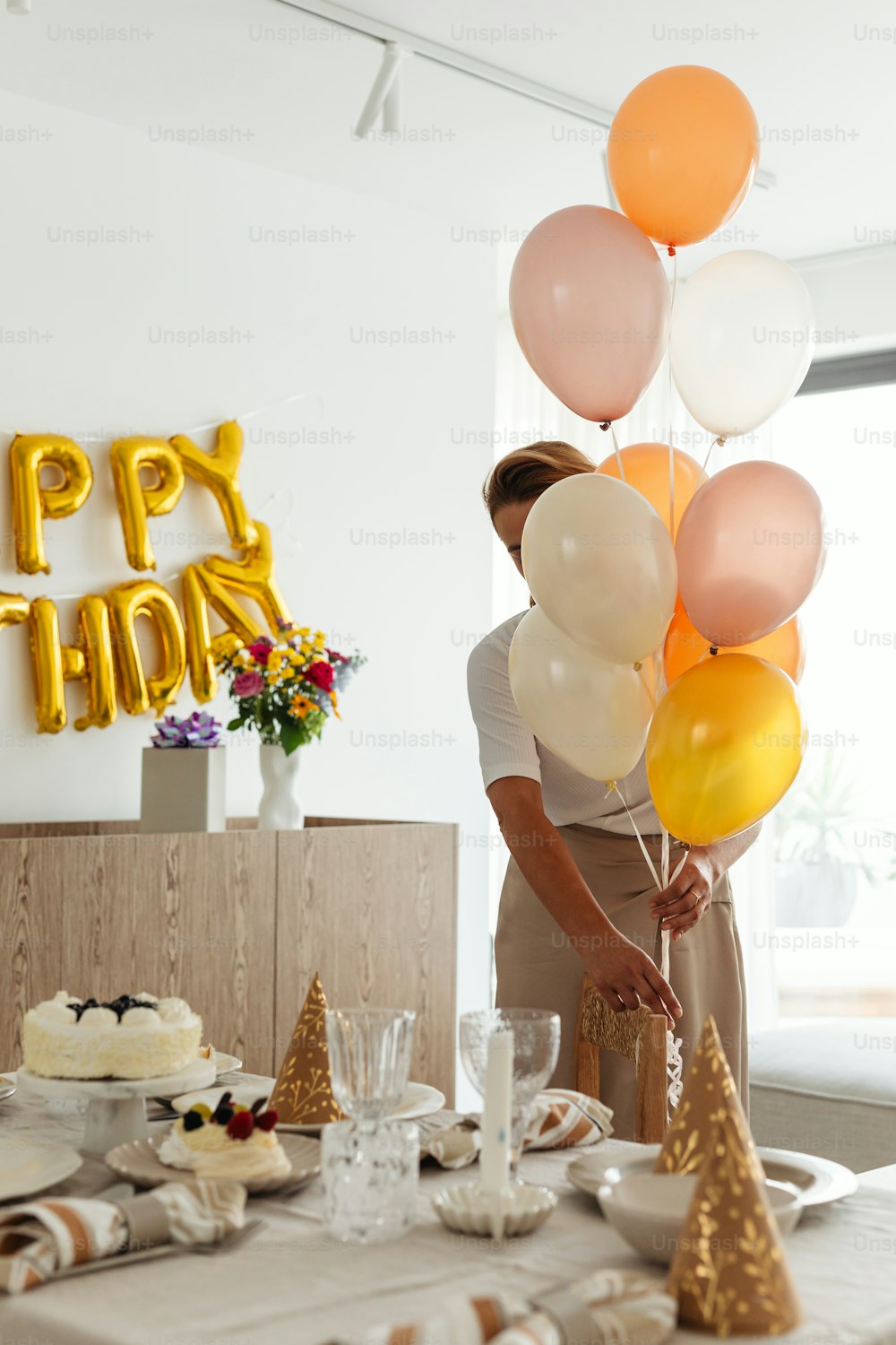 a woman holding a bunch of balloons over a table