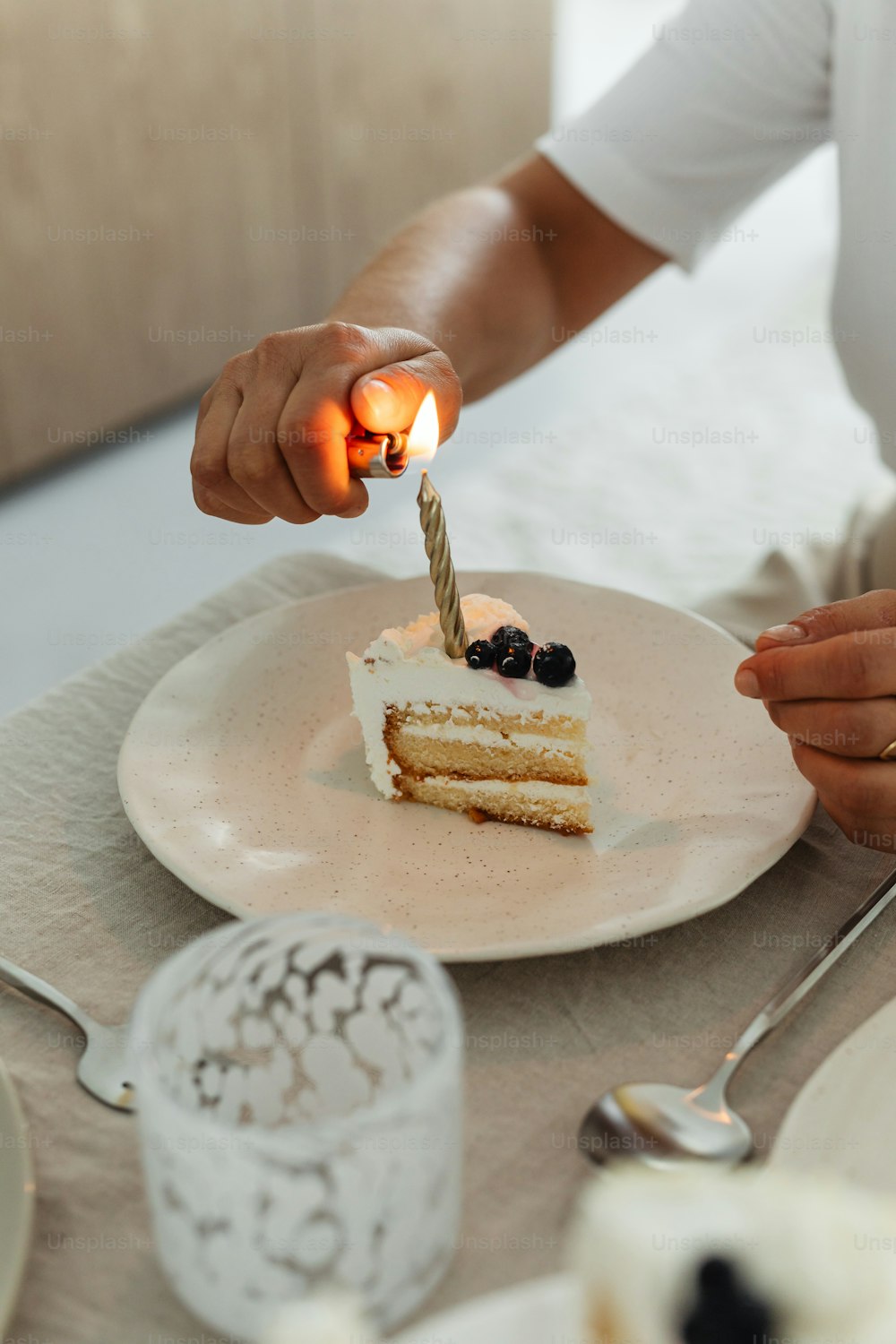 eine Person, die eine Kerze auf einem Stück Kuchen anzündet