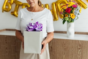 a woman holding a gift box with a purple bow