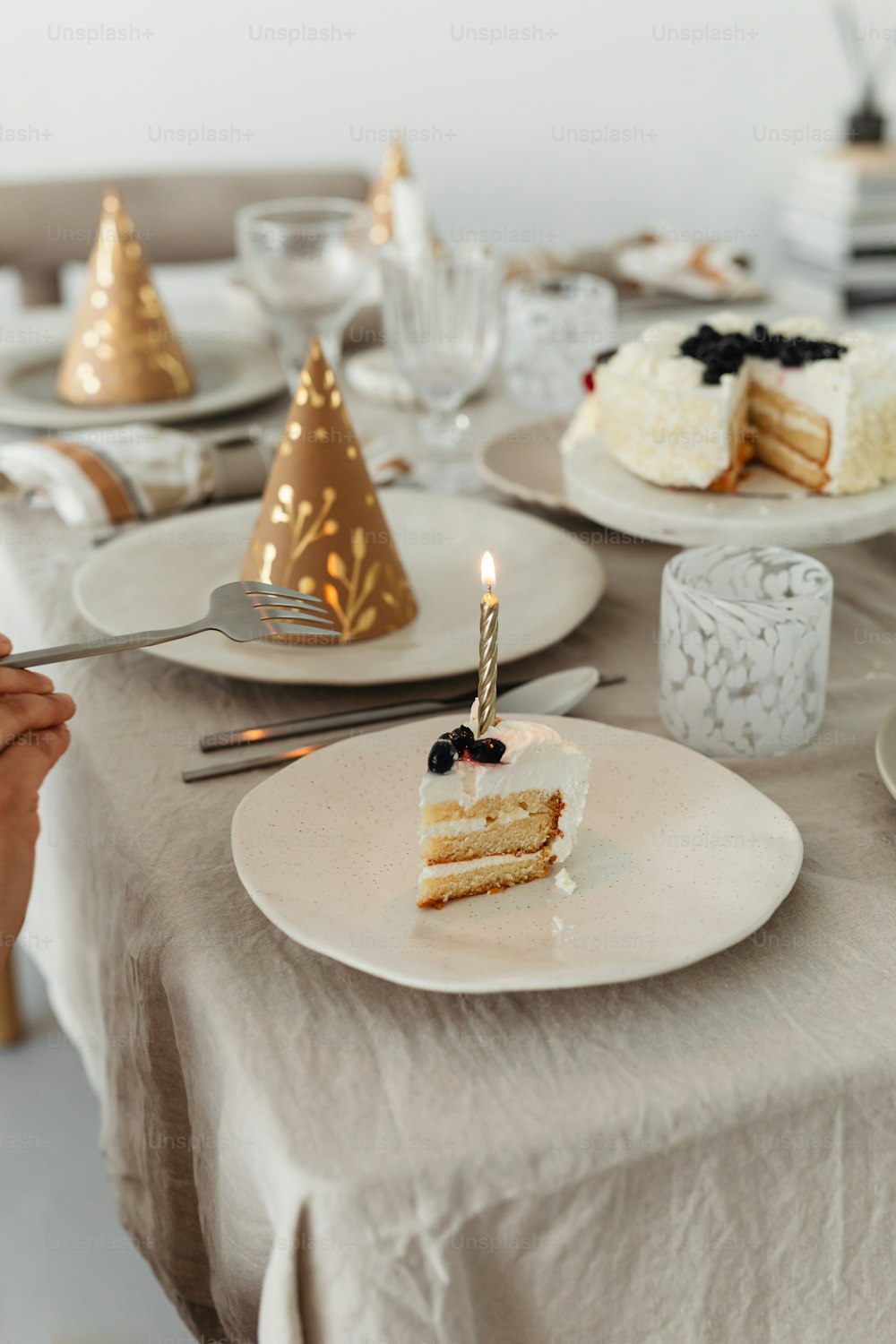 a table topped with a slice of cake and a lit candle