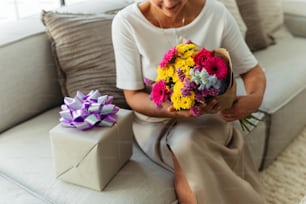 a woman sitting on a couch holding a bouquet of flowers