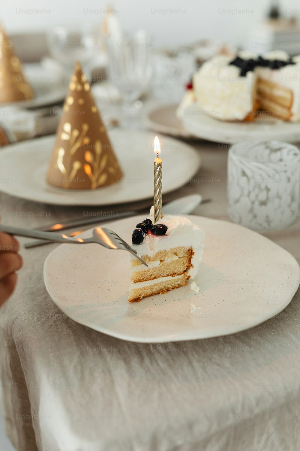 une tranche de gâteau sur une assiette avec une bougie allumée
