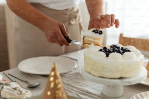 a person cutting a piece of cake with a knife