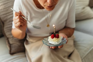 eine Frau, die einen kleinen Kuchen mit einer Kerze darauf hält