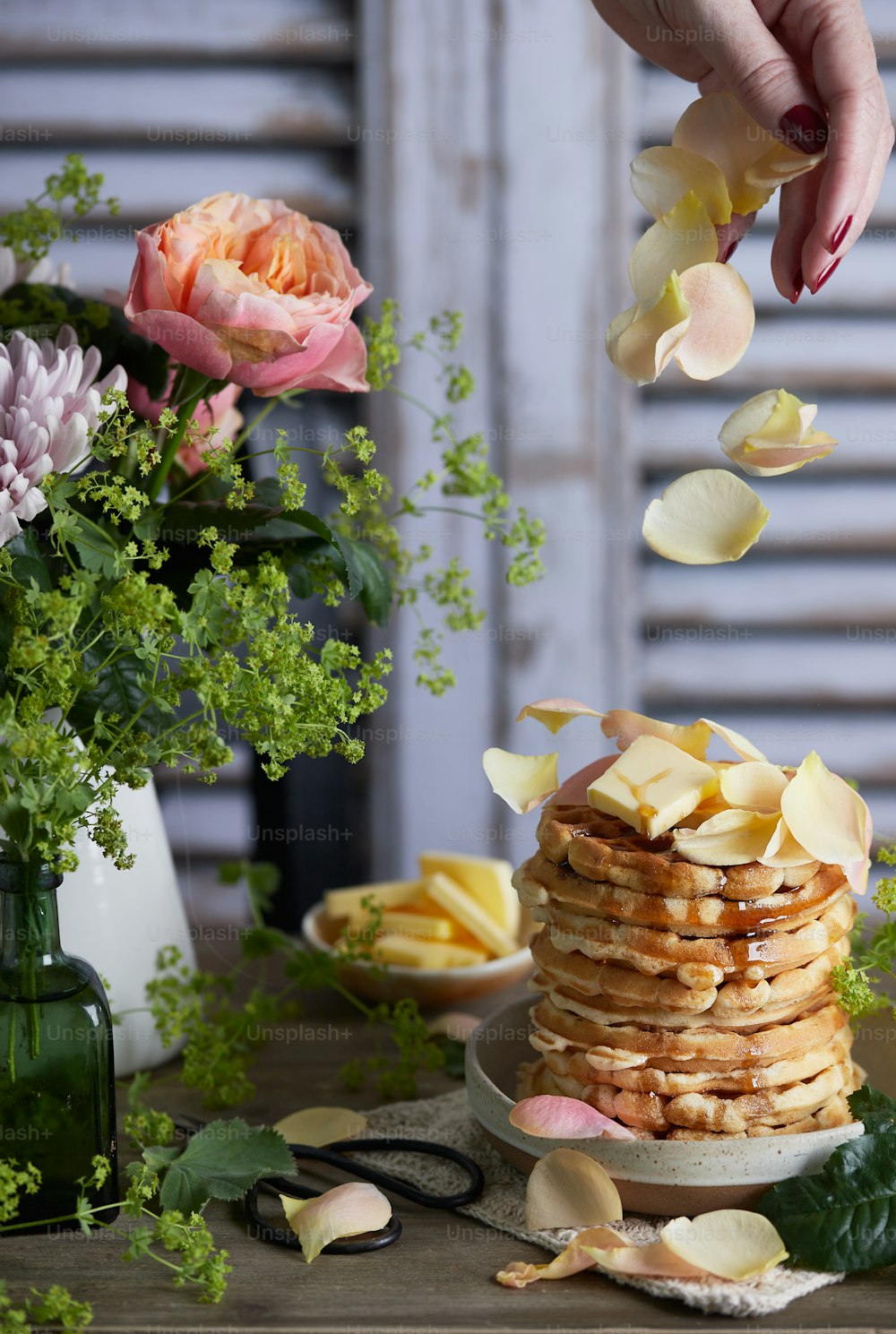 a stack of pancakes on a plate with flowers in the background