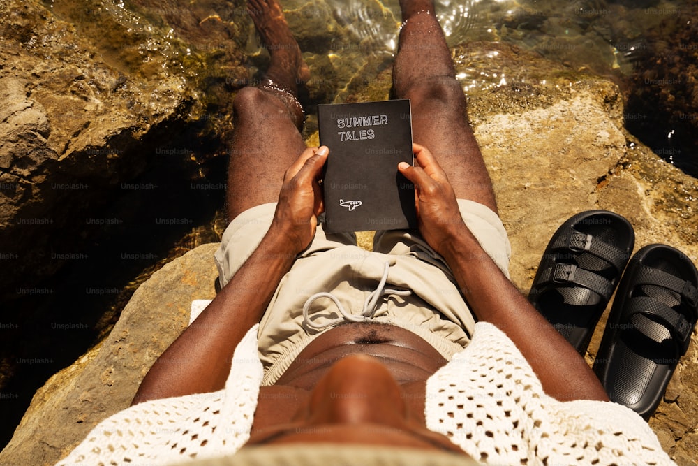 une personne allongée sur un rocher avec un livre