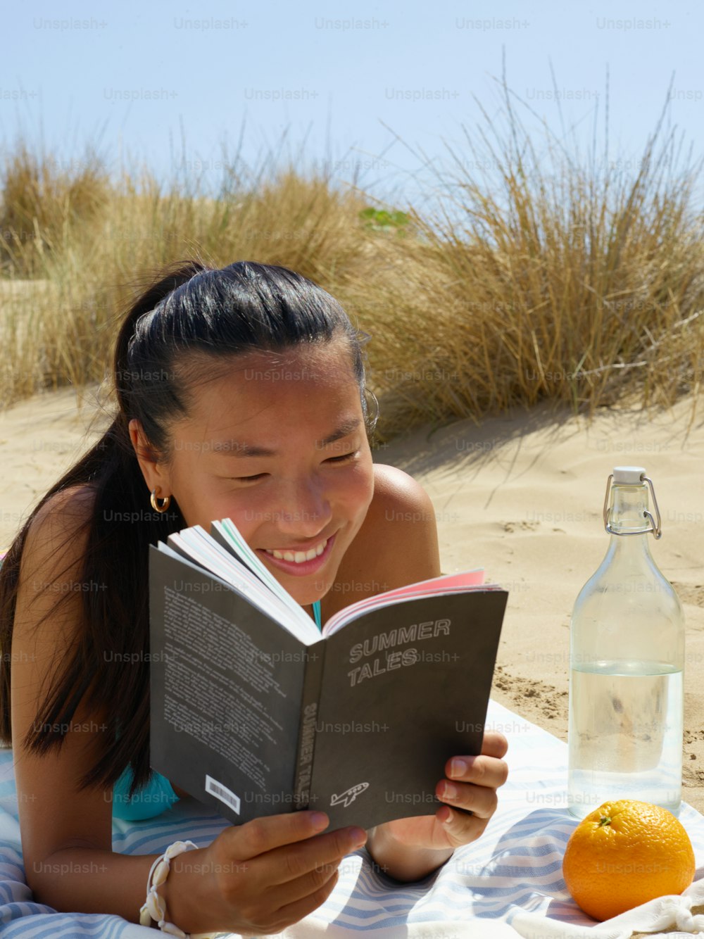 a girl reading a book on the beach