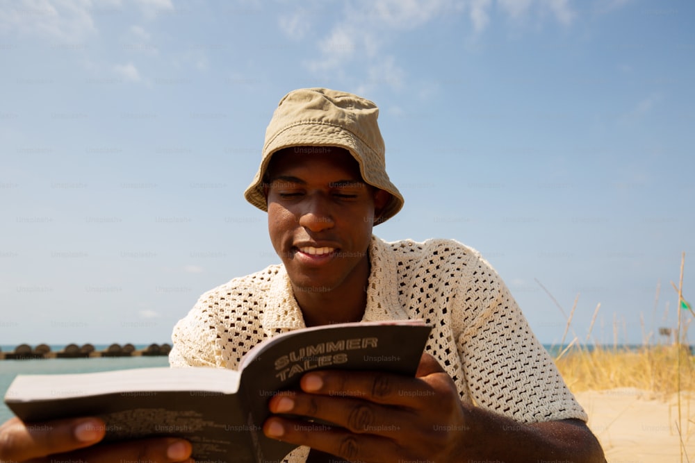 Un homme assis sur une plage en train de lire un livre