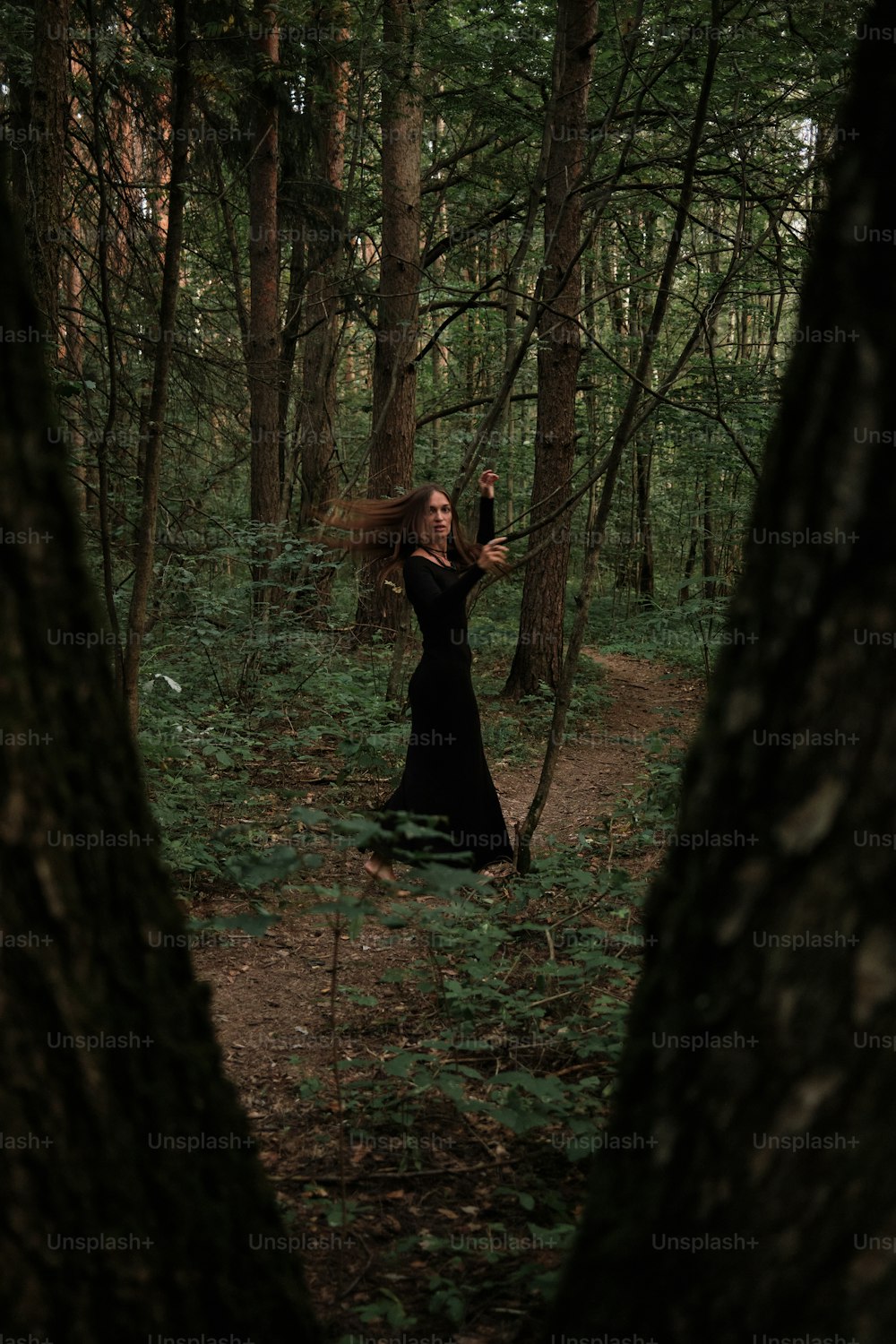 a woman in a black dress in the woods