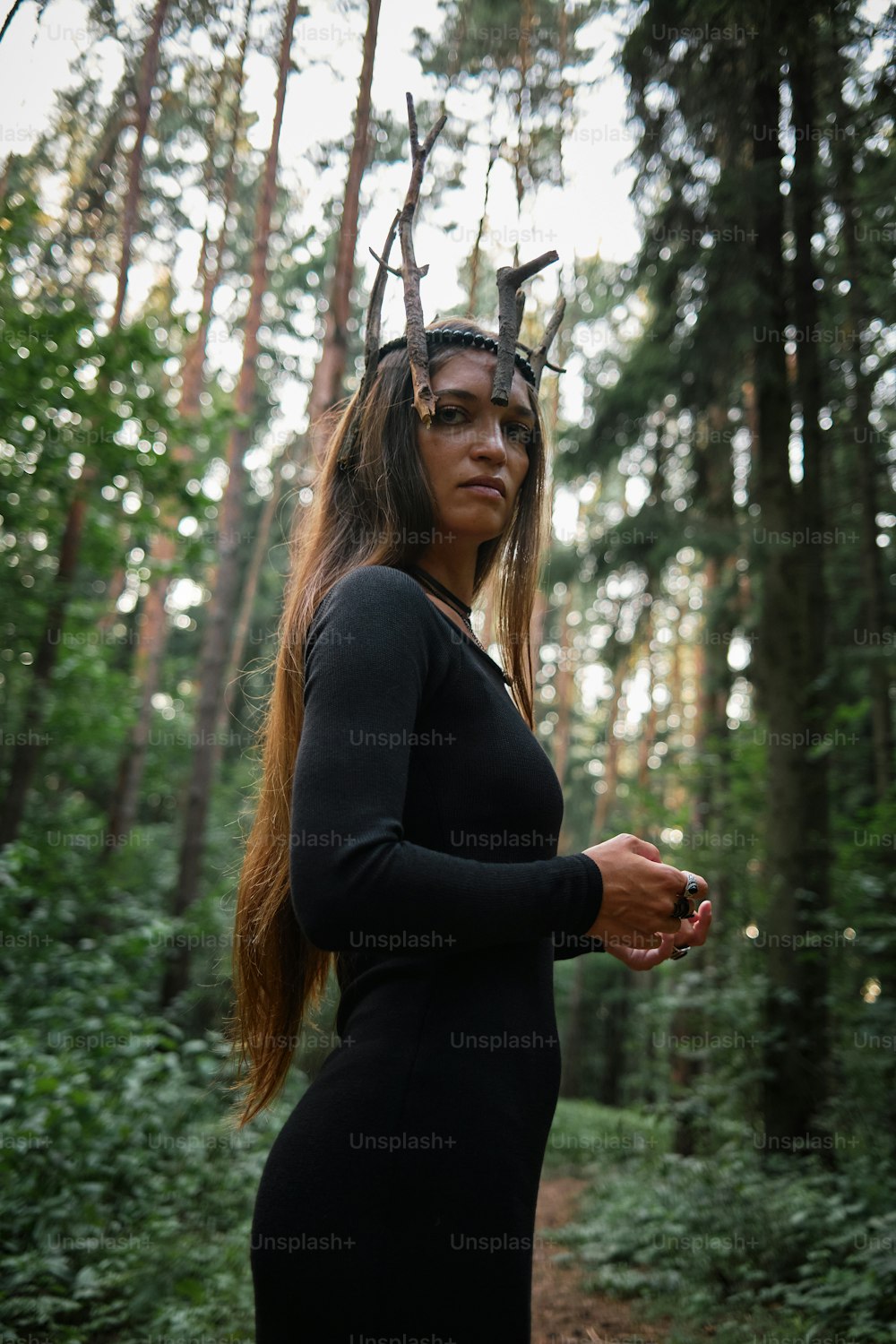 Una mujer en un bosque con cuernos en la cabeza