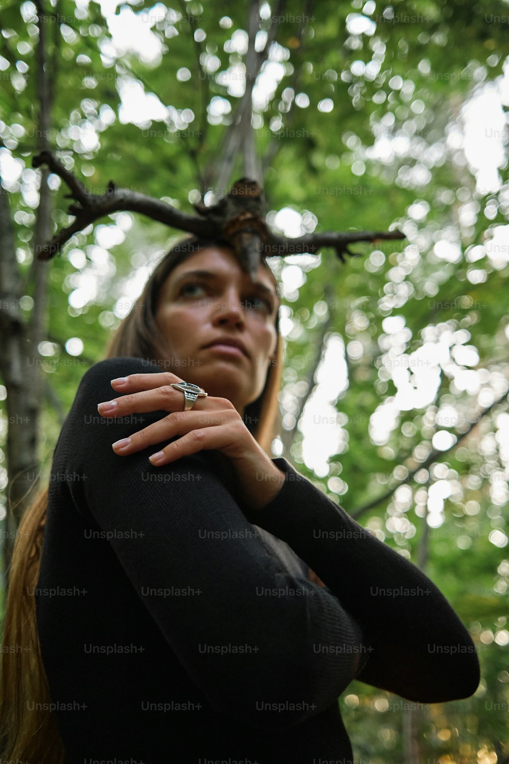 a woman wearing a ring standing in a forest
