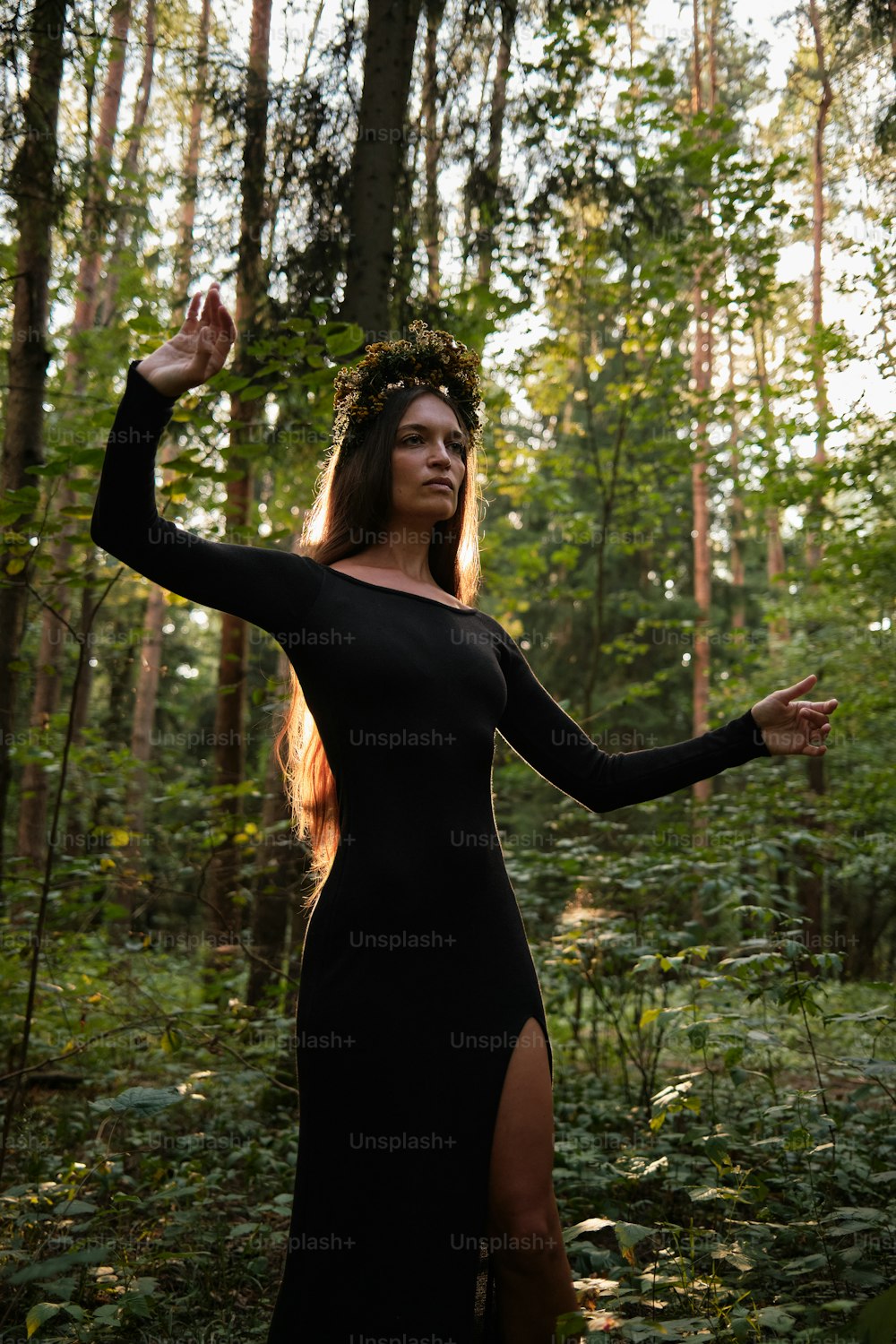 a woman in a black dress standing in a forest