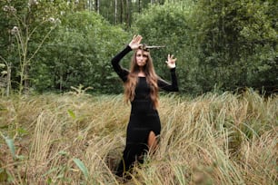 a woman in a black dress standing in tall grass
