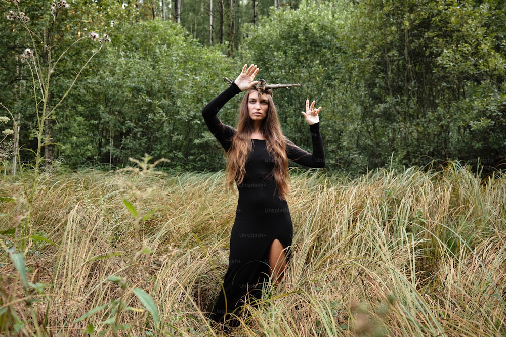 a woman in a black dress standing in tall grass