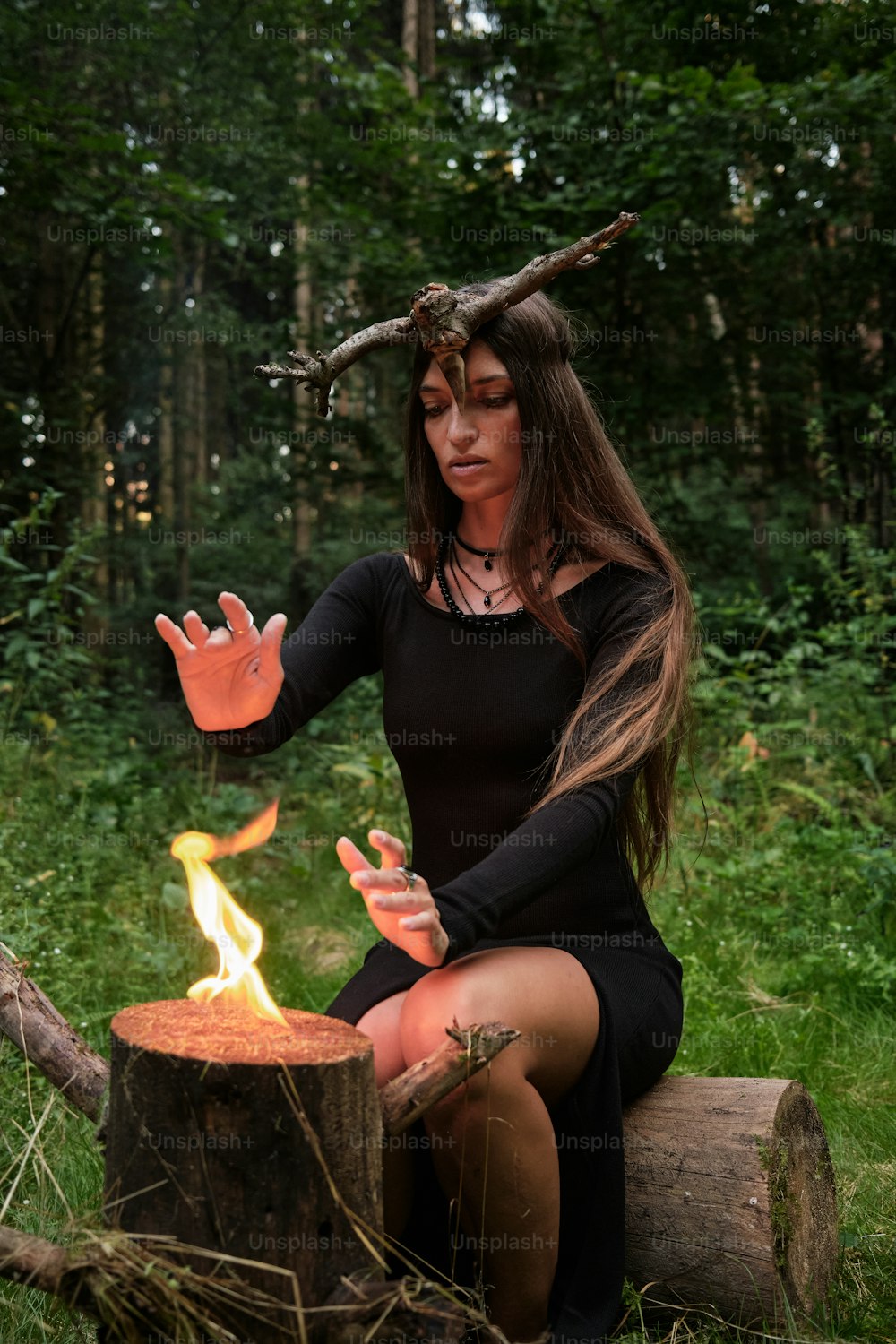 a woman in a black dress sitting on a log