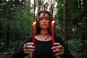 a woman holding two candles in front of her face