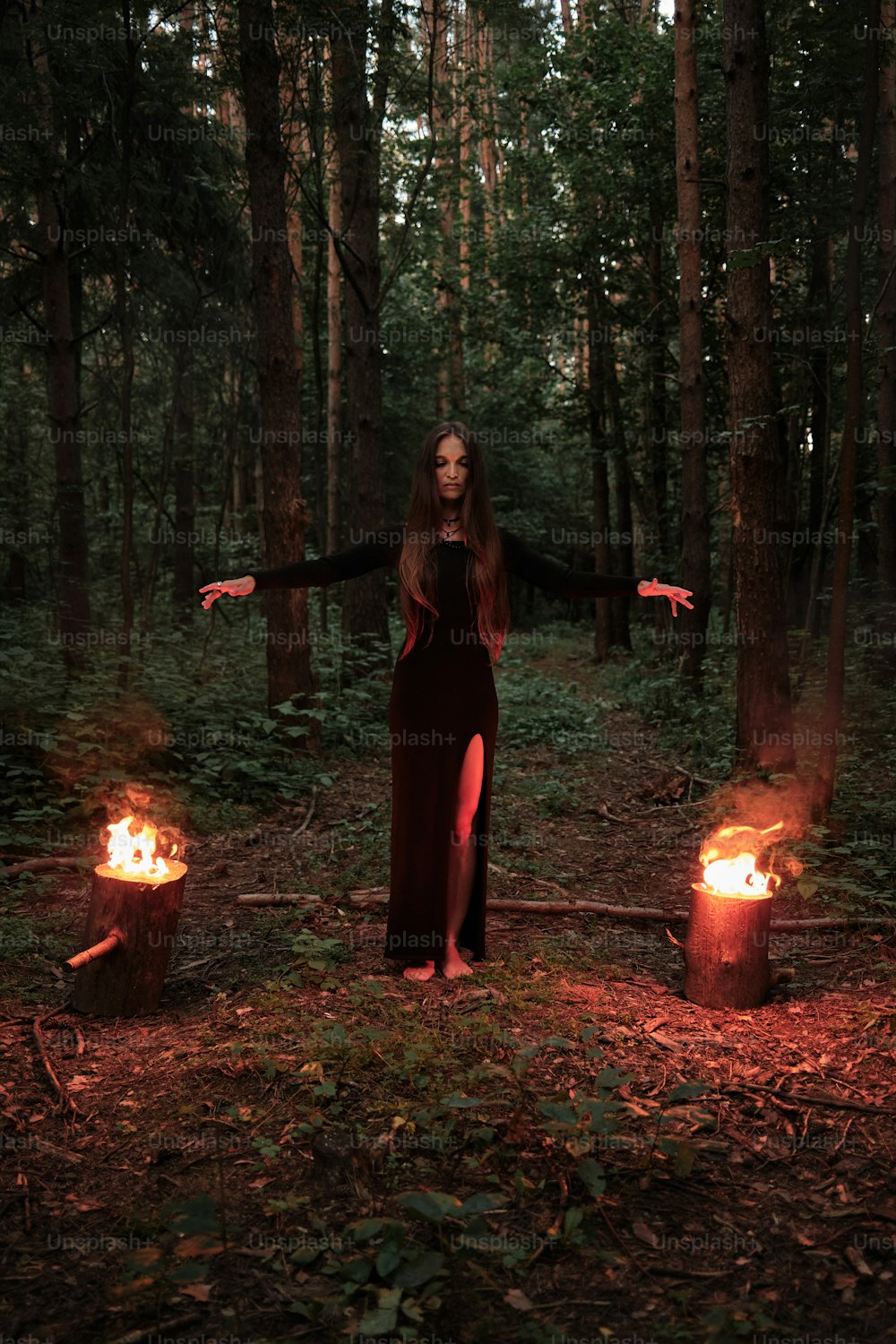 Una donna in piedi nel bosco con le braccia tese