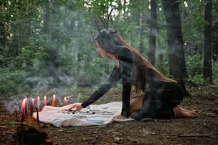 숲 속에서 담요를 덮고 앉아 있는 여��자