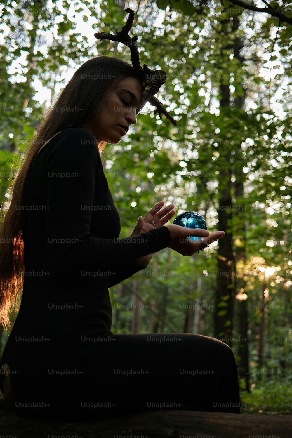 a woman sitting on a log in the woods