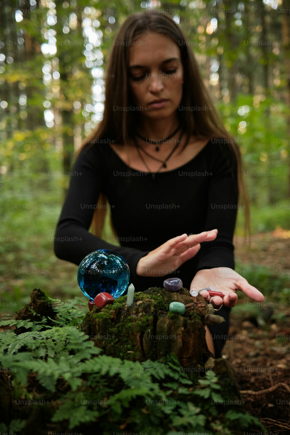 a woman sitting in the woods holding out her hands