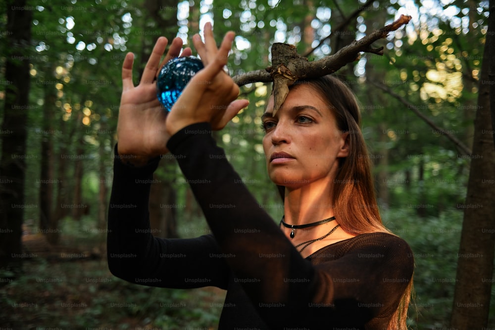 a woman holding a blue ball in the woods