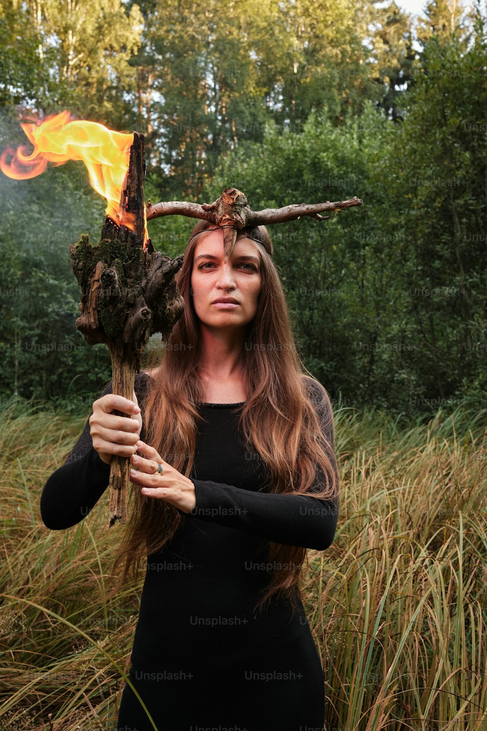 a woman in a black dress holding a stick with flames on it