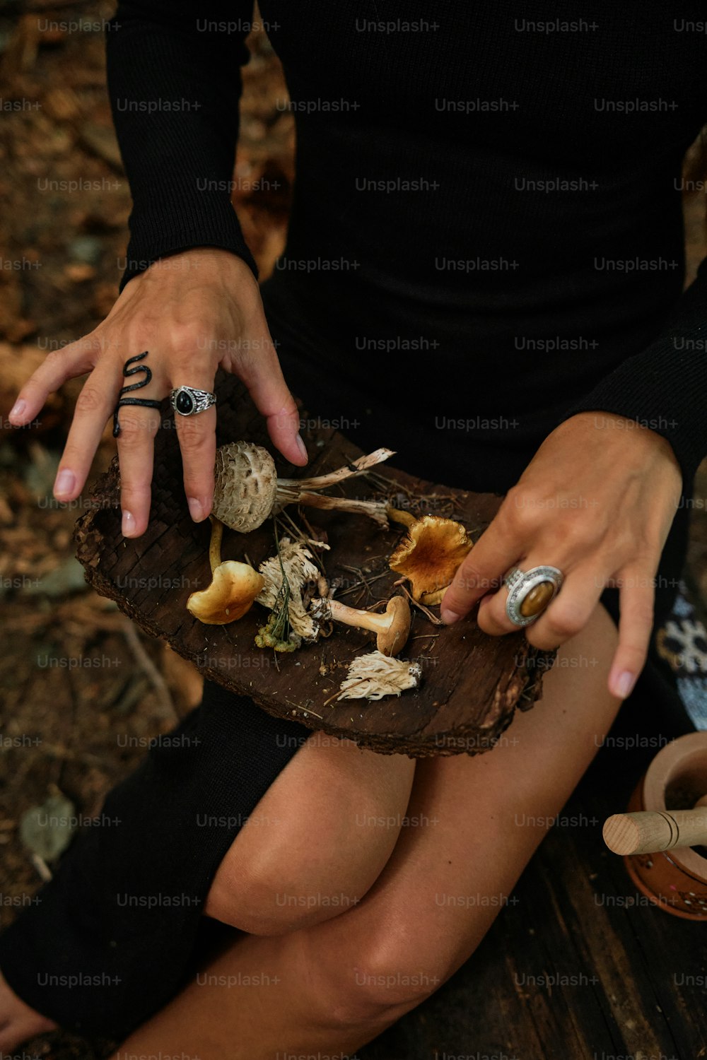a woman sitting on a bench holding a tray of mushrooms
