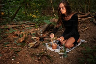a woman sitting on a blanket in the woods