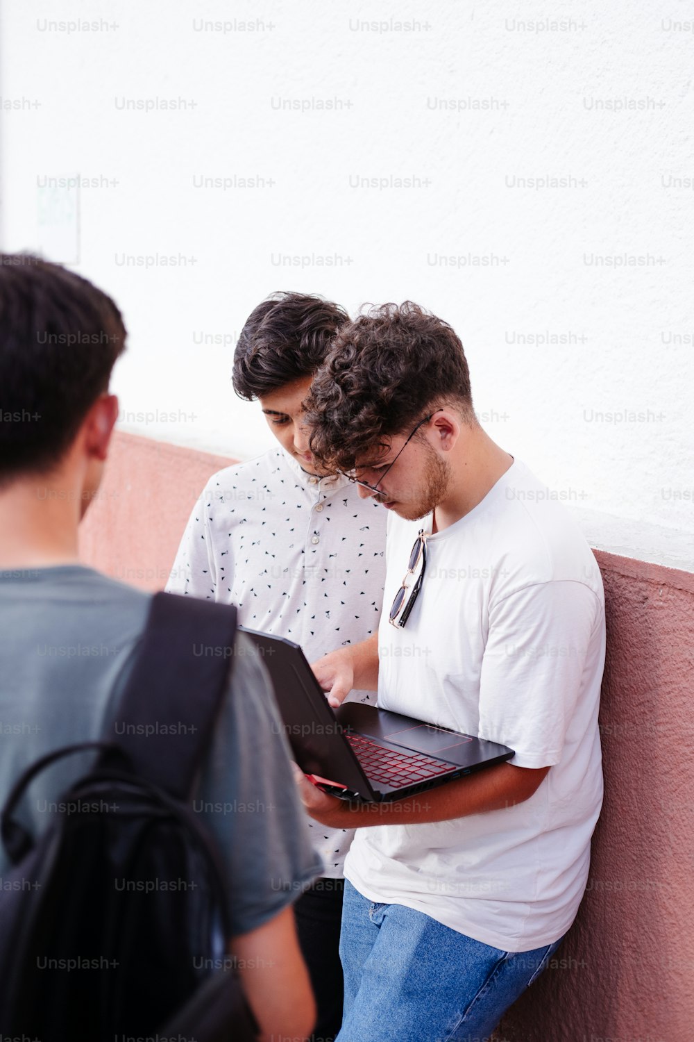 two men standing next to each other looking at a laptop