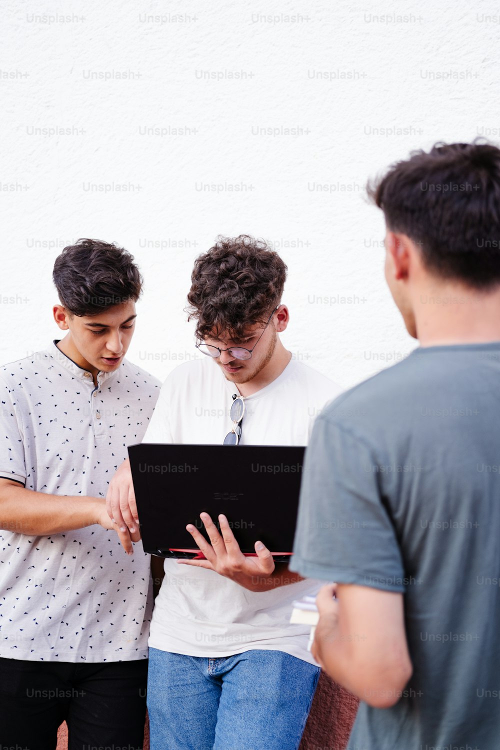 ノートパソ�コンの周りに立つ若い男性のグループ