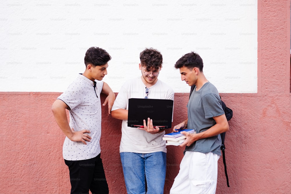 três rapazes de pé um ao lado do outro olhando para um laptop
