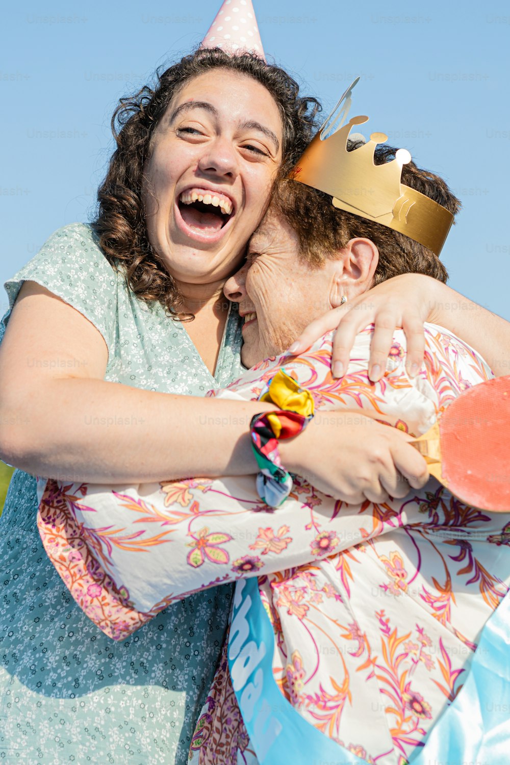a woman hugging another woman with a crown on her head