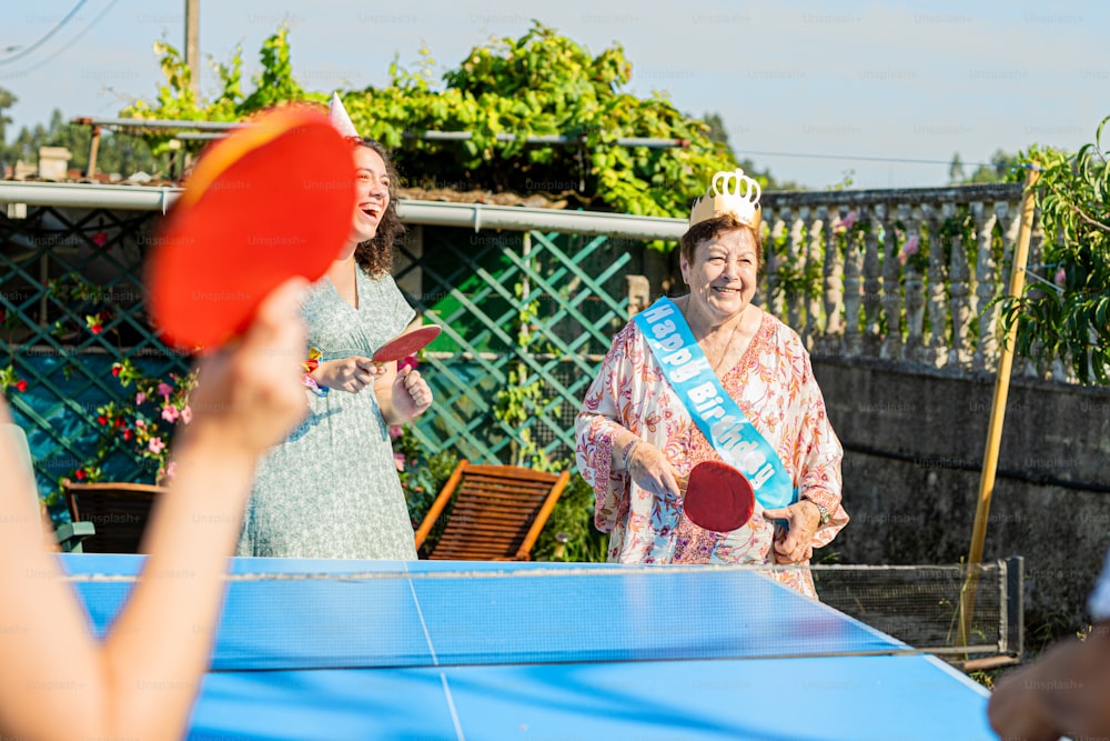 a woman holding a ping pong paddle next to another woman