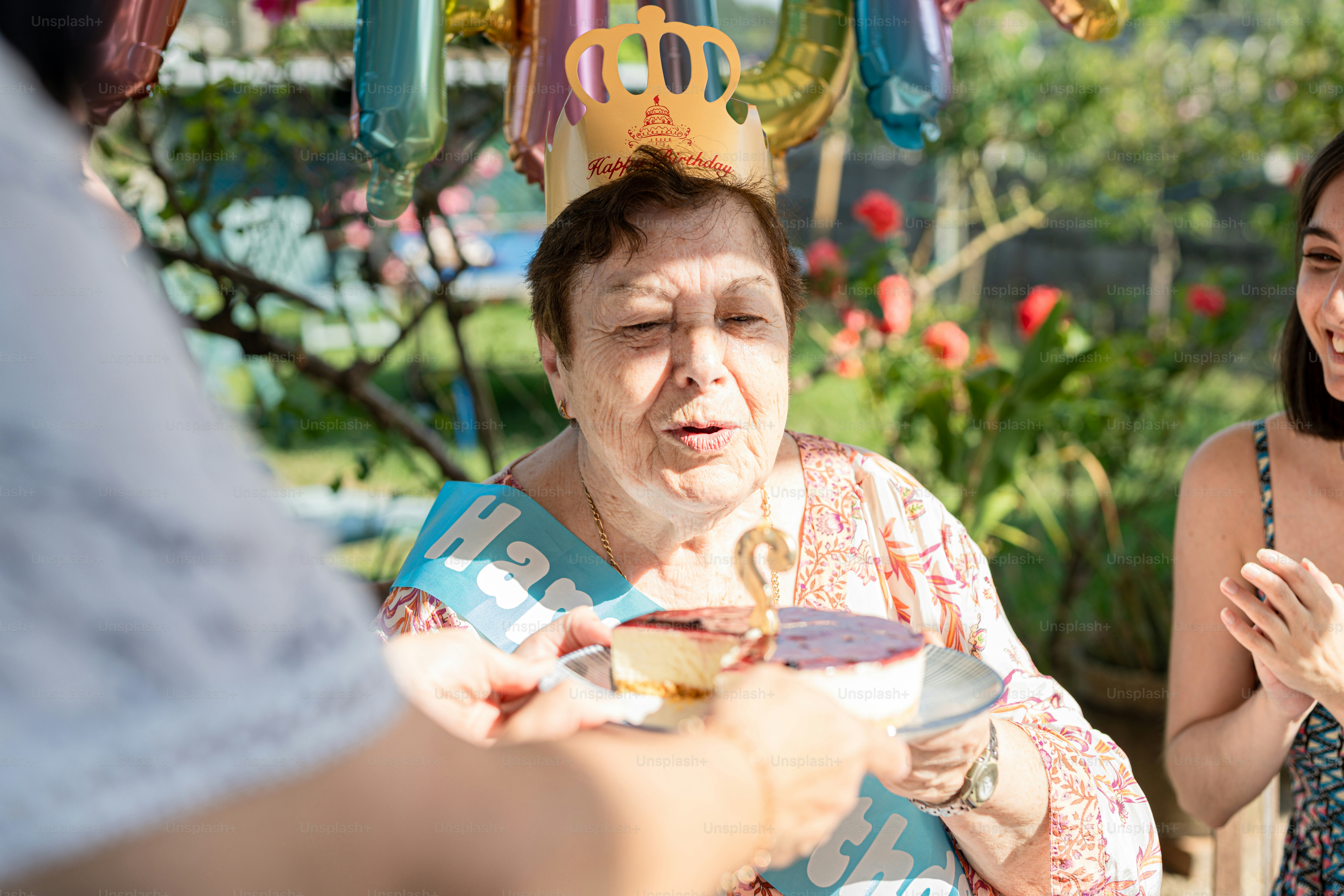 a woman in a birthday hat is handing out a piece of cake