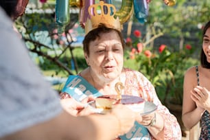 a woman in a birthday hat is handing out a piece of cake