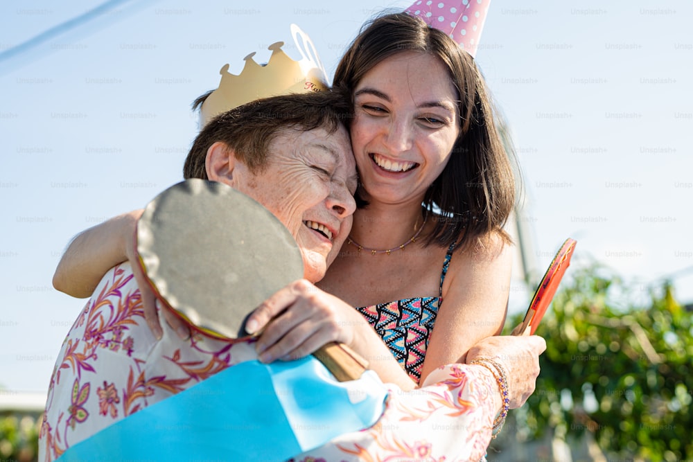 a woman is hugging a child with a birthday hat on