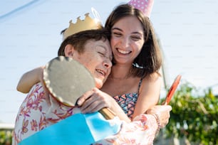 Una mujer abraza a un niño con un sombrero de cumpleaños puesto