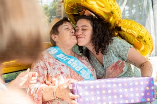 Zwei Frauen küssen sich, während sie ein Geschenk halten