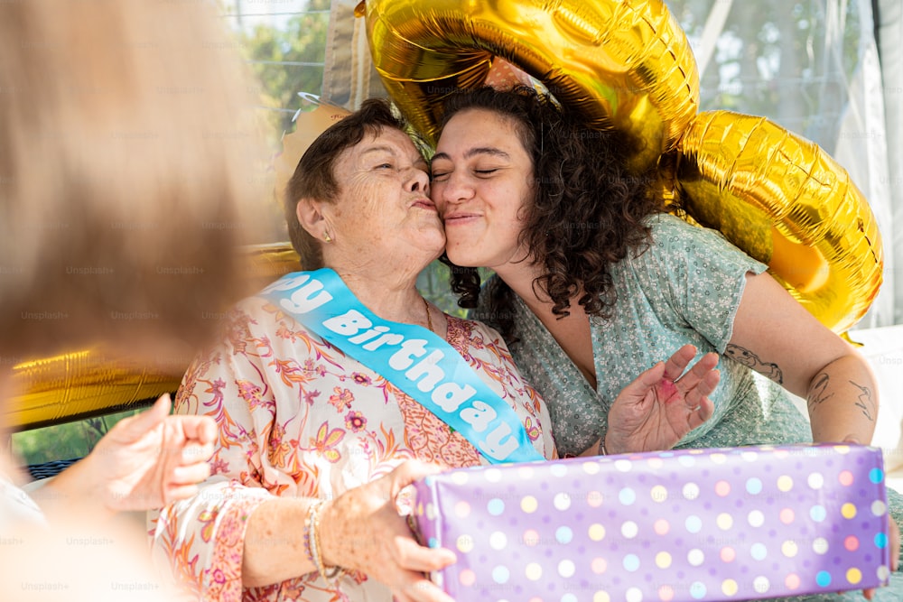 two women kissing each other while holding a present